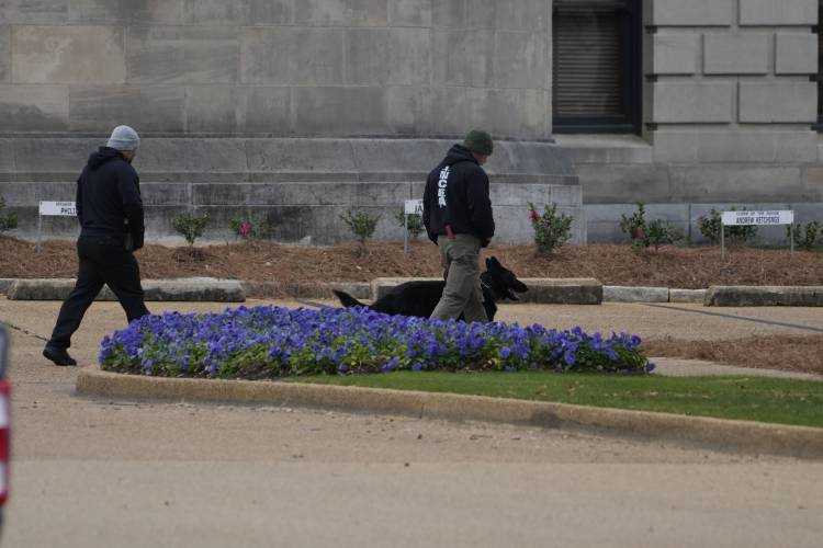 An ordinance sniffing dog patrols the Mississippi State Capitol grounds as Capitol Police respond to a bomb threat at the state building in Jackson, Miss., Wednesday morning, Jan. 3, 2024. The structure was emptied and the grounds cleared of vehicles as officers investigated. (AP Photo/Rogelio V. Solis)