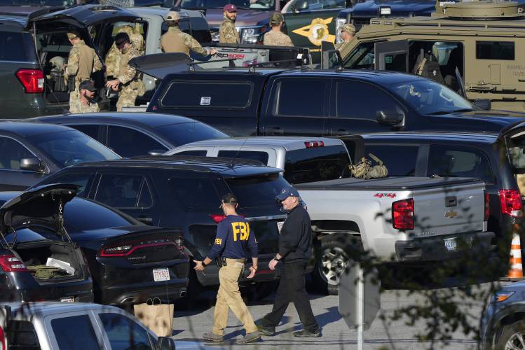 Law enforcement personnel are staged in a school parking lot during a manhunt for Robert Card in the aftermath of a mass shooting in Lewiston, Maine, Oct. 27, 2023. Despite the warning by Card's friend and fellow Army reservist Sean Hodgson, which came alongside a series of other glaring red flags, Army officials discounted the warnings and ultimately did not stop Card from committing Maine's deadliest mass shooting when he killed multiple people in Lewiston. (AP Photo/Matt Rourke,...