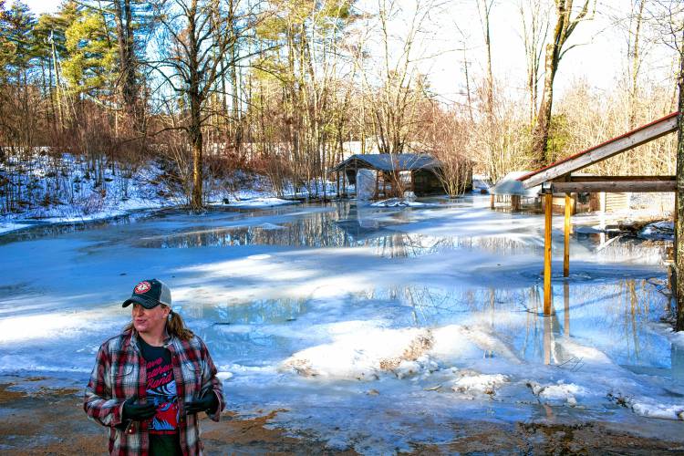 Tessa Dyer stands in her backyard that is unrecognizable under the water and ice that has engulfed her property in Loudon, off of Route 106 on Wednesday, January 10, 2024.