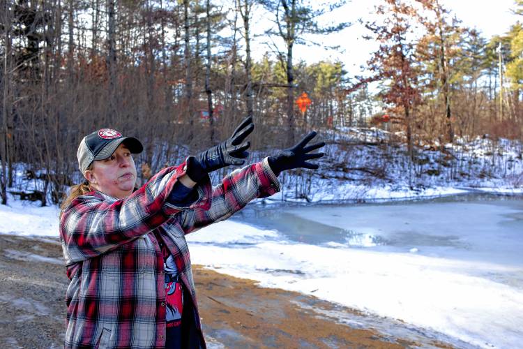 Tessa Dyer stands in her backyard that is unrecognizable under the water and ice that has engulfed her property in Loudon, off of Route 106 on Wednesday, January 10, 2024.