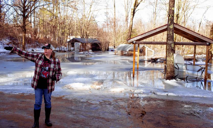 Tessa Dyer stands in her backyard that is unrecognizable under the water and ice that has engulfed her property in Loudon, off of Route 106 on Wednesday, January 10, 2024.