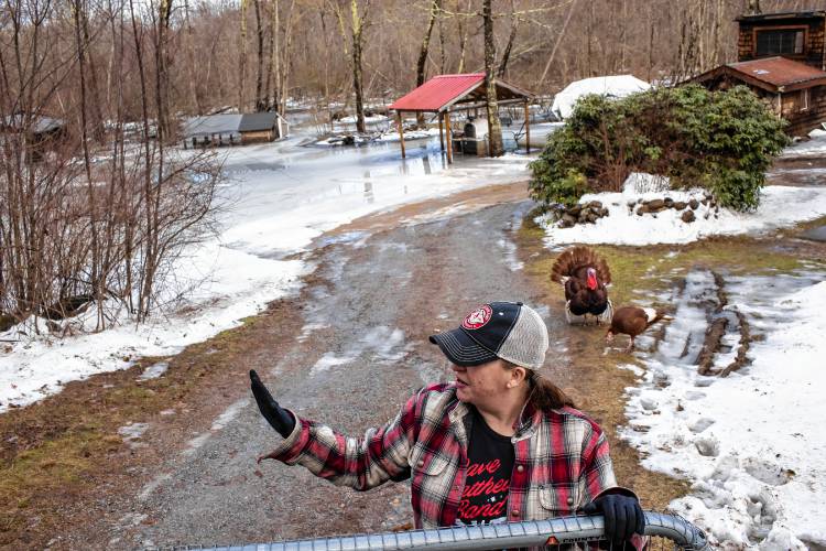 Tessa Dyer stands in her backyard that is unrecognizable under the water and ice that has engulfed her property in Loudon, off of Route 106 on Wednesday, January 10, 2024.