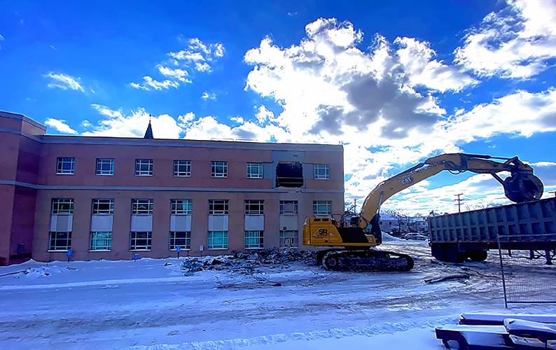 An excavator removes debris from the former Department of Justice building off of Capitol Street in Concord as the demolition of the building started on Wednesday, January 17, 2024.