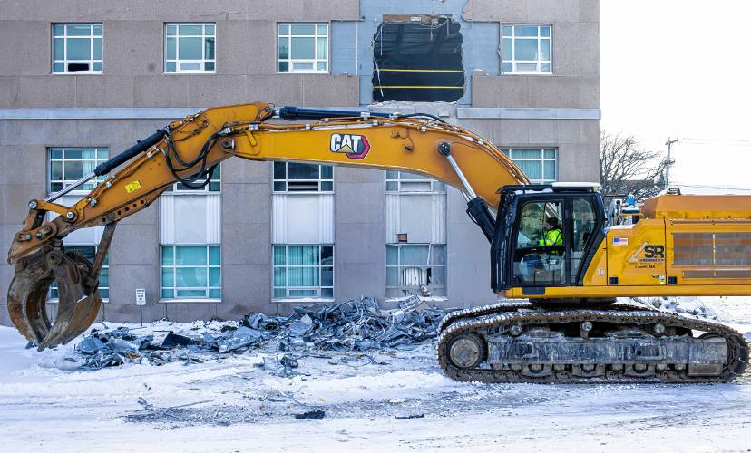 An excavator removes debris from the former Department of Justice building off of Capitol Street in Concord as the demolition of the building started on Wednesday.