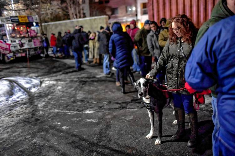 Heather Dalbach of Sutton waits in line in the freezing cold with her service dog, Nessie, outside the Courtyard by Marriot in Concord on Friday night, January 19, 2024.