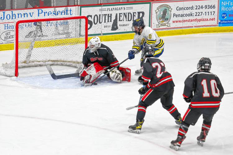 Luke Hartshorn tries to poke the puck through the legs of Bedford goalie Tristan Kerr during Wednesday night’s matchup at Everett Arena.