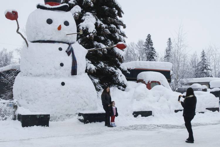 FILE - Nihal Mico takes a photo of her sister-in-law Isil Mico as she poses with her daughter Lorena in front of Snowzilla, a snowman measuring more than 20 feet tall, in Anchorage, Alaska, on Jan. 10, 2024. Much of Alaska has plunged into a deep freeze, with temperatures well below zero and Anchorage seeing some of its coldest temperatures in years as the mayor of the state’s largest city opened warming facilities for those who are homeless or who don't have reliable heating. (AP...