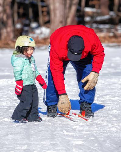 Keith Nelson picks up the crosscounty skis for his granddaughter Mai, 3, after she finished her crosscountry lesson at  The Concord Community Nordic Trails at Beaver Meadow Golf Course on Sunday, February 4, 2024. The Sunday event paired a low-key freestyle community citizens race with a free Learn-to-Ski clinic for those new to the sport.