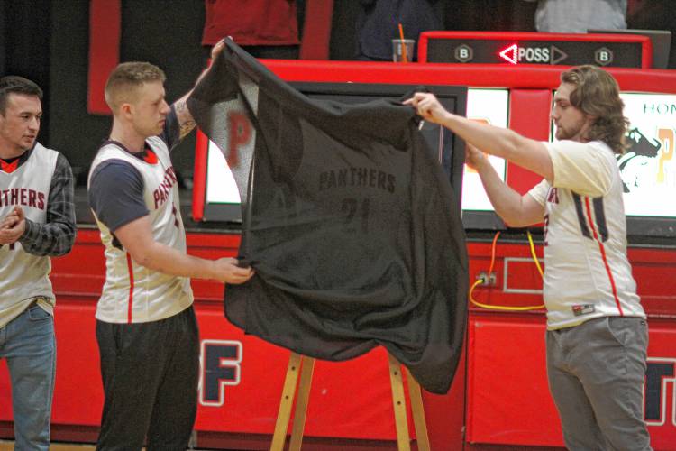 Cam Darrah (left) and Casey Clark unveil a framed No. 21 Gabe Anthony jersey presented to Anthony’s family. Pittsfield held a ceremony to remember Anthony, who died in December, before the boys’ basketball game on Monday night, Feb. 12.