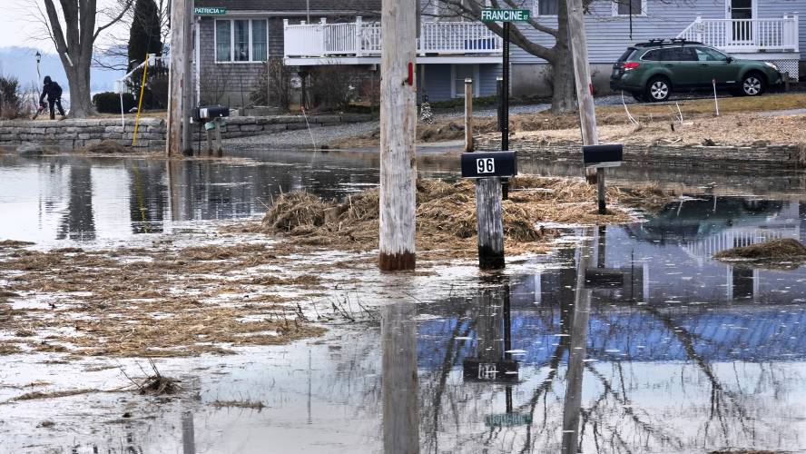 While her road and neighbor's mailboxes are covered by high tide waters, Diane Levesque, left, uses a leaf blower to clear marsh grass from her yard, which was deposited during January 2024 storms, Friday, Feb. 9, 2024, in Hampton, N.H. Scientists say the back-to-back storms that lashed the Northeast in January were more of a sign of things to come than an anomaly. Many scientists who study the intersection of climate change, flooding, winter storms and sea level say such storms...