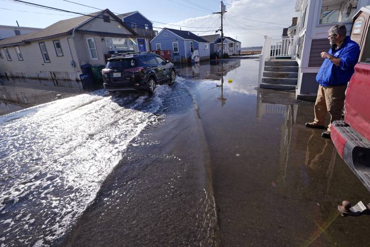 Haim Levy watches as a neighbor drives through high tide waters, covering the road with sea water, at his cottage near Hampton Beach, which was flood damaged during January 2024 storms, Friday, Feb. 9, 2024, in Hampton, N.H. Scientists say the back-to-back storms that lashed the Northeast in January were more of a sign of things to come than an anomaly. Many scientists who study the intersection of climate change, flooding, winter storms and sea level say such storms will arrive...