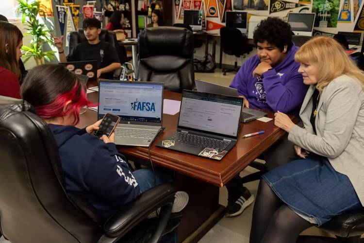 In this file photo, Lynda McGee, right, a college counselor, helps students fill out the FASFA at Downtown Magnets High School.
