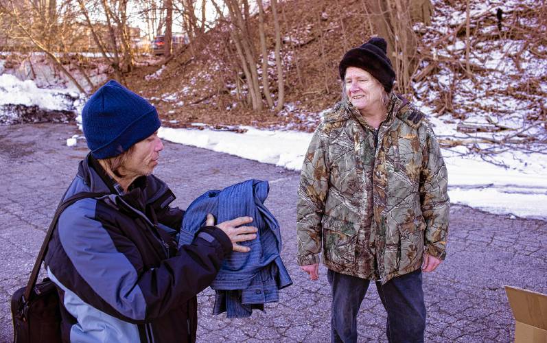 Rebecca Carlman hands out a shirt and a blanket to Brian Demerett of Concord off of Storrs Street in Concord on Feb. 8.