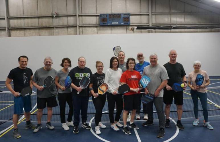 Nancy Morton, center in red, meets a group at Gilford Hills Tennis & Fitness Club regularly to play pickleball, a sport similar to tennis played with a wiffleball.