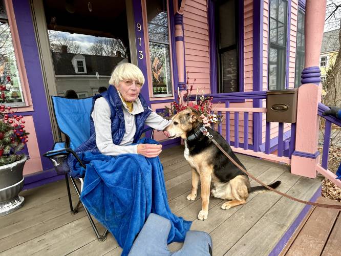 Barbara Filion enjoys a quiet morning on her front porch in Portsmouth with her neighbor's dog Buddy.