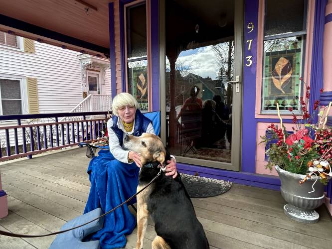 Barbara Filion enjoys a quiet morning on her front porch in Portsmouth with her neighbor's dog Buddy.