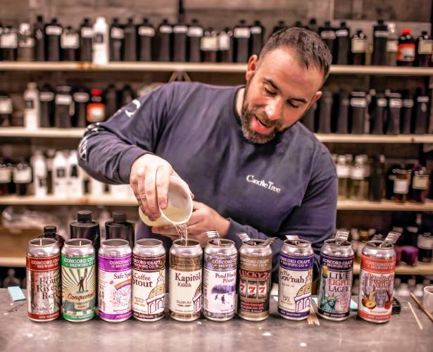 Ross Mingarelli pours the hot soy wax for his specialty beer can candles at his downtown shop in Concord.