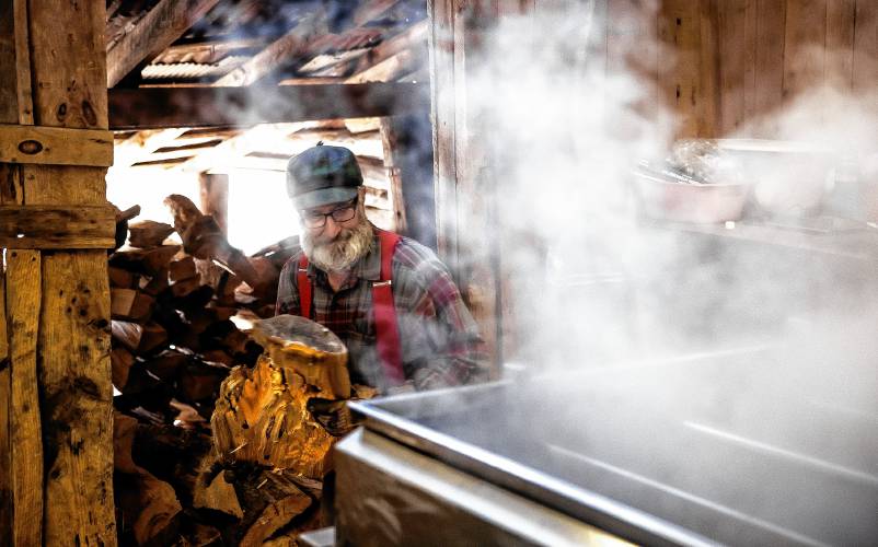 Tim Courser gets ready to load some more wood into the evaporator in their sugar house that he and his brother built nearly 50 years ago.