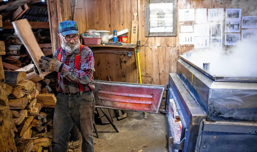 Tim Courser gets ready to load some more wood into the evaporator in their sugar house that he and his brother built nearly 50 years ago.