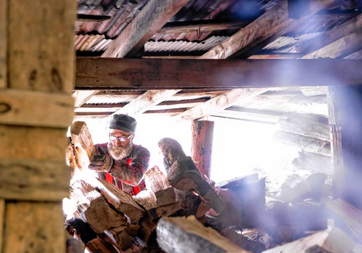 Tim Courser stacks wood in the sugar house that he and his brother built nearly 50 years ago.