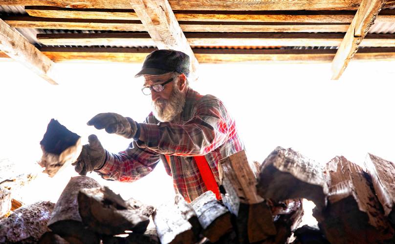 Tim Courser stacks wood in the sugar house that he and his brother built nearly 50 years ago.