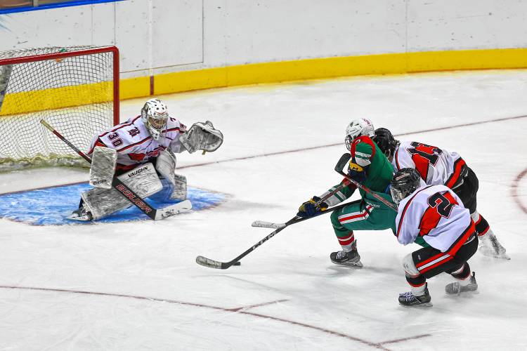 Caden Mix (3) drives to the net for PAC as Berlin-Gorham's Evan Poulin (2) and Michael Cote (13) try to knock him off the puck and goalie Kolin Melanson waits for a shot.