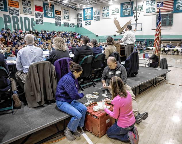 Hopkinton poll attendants Eric Rix (left), Ian Tewksbury and and Elizabeth Sides count the SB2 votes behind the podium during the school district meeting Saturday.