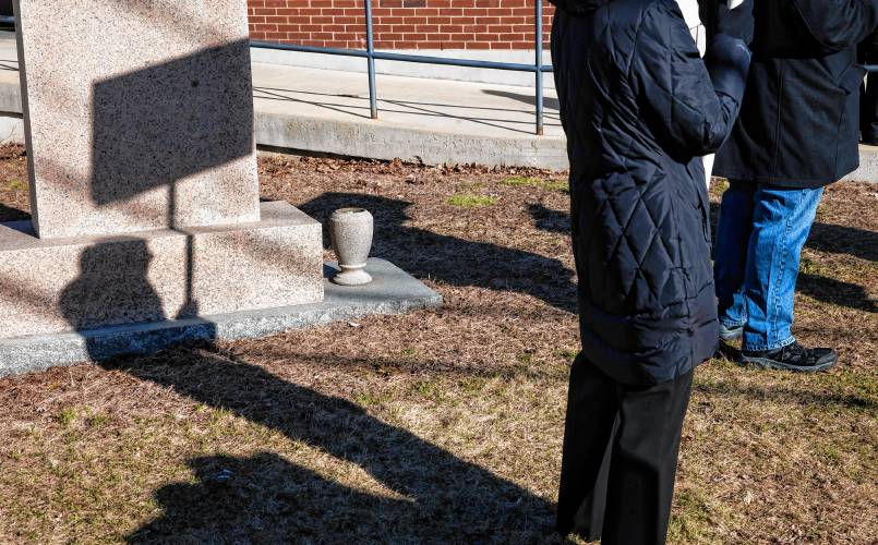 Kathleen Pelissier is reflected in a shadow as she stands behind a small heater as greets voters in front of the St. John’s Parish Hall in Allenstown on Tuesday, March 12, 2024.