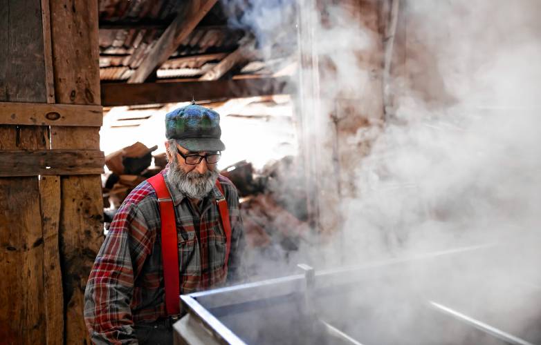 Tim Courser gets ready to load some more wood into the evaporator in their sugar house that he and his brother built nearly 50 years ago.