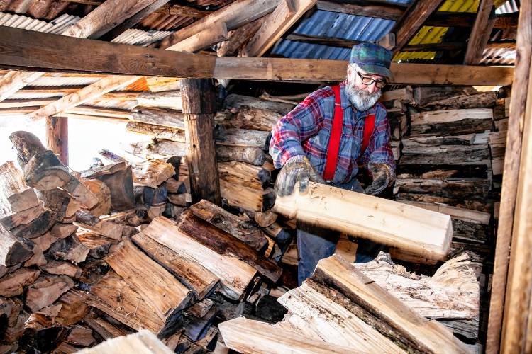 Tim Courser stacks wood in the sugar house that he and his brother built nearly 50 years ago.