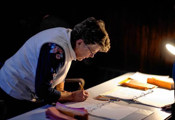 Supervisor of the Checklist Christine Perkins for Warner checks in a resident at the town hall at the packed house Wednesday night.