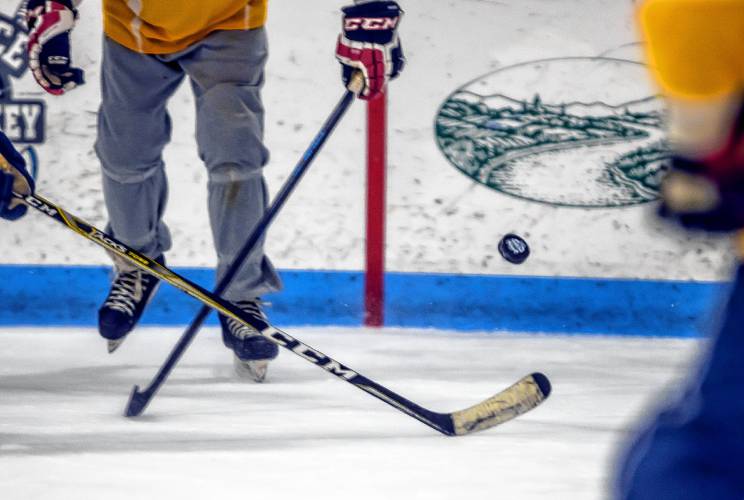 A puck flies during a morning game at the Black Ice Hockey Tournament at the Tri-Town Arena in Hooksett on Friday, March 22, 2024.