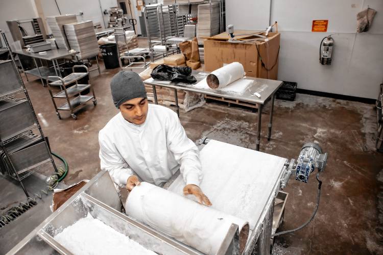 Aissa Sweets owner, Amhad Aissa, places flour in the roller that flattens the paper-thin dough to make the custom Baklava at his production facility on Hall Street in Concord.
